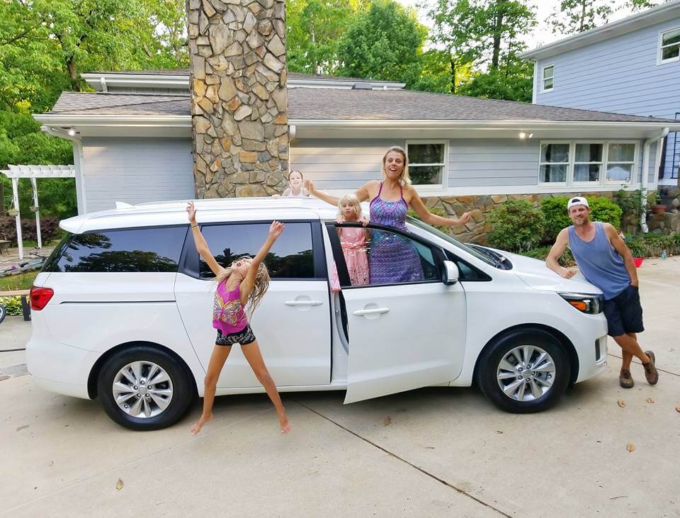 family posing in front of mini van