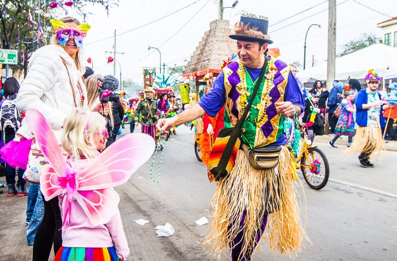 family dressed up on streets getting beads at mardi gras