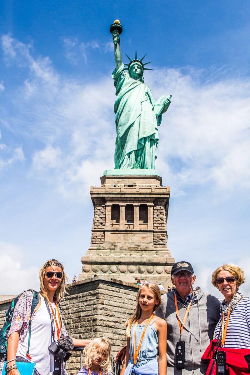 family posing in front of Statue of Liberty