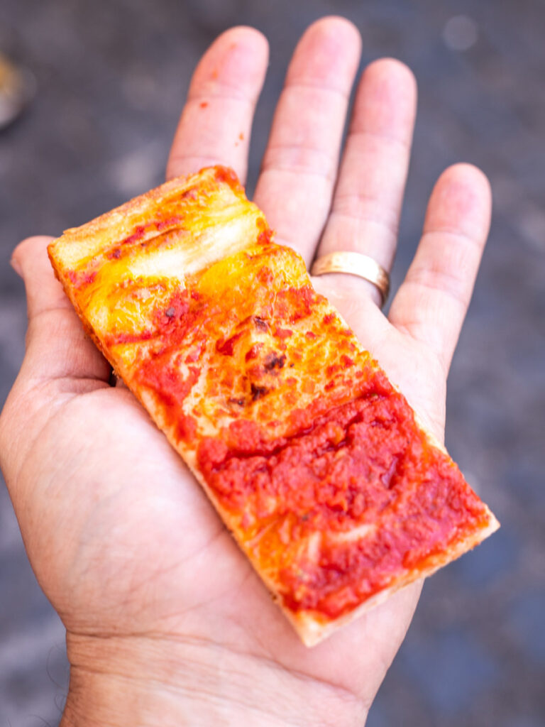 person holding red pizza in hand