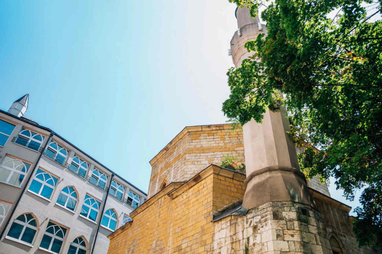 The Bajrakli Mosque in Belgrade, showcasing its distinctive minaret against a clear sky, with the surrounding area partially visible