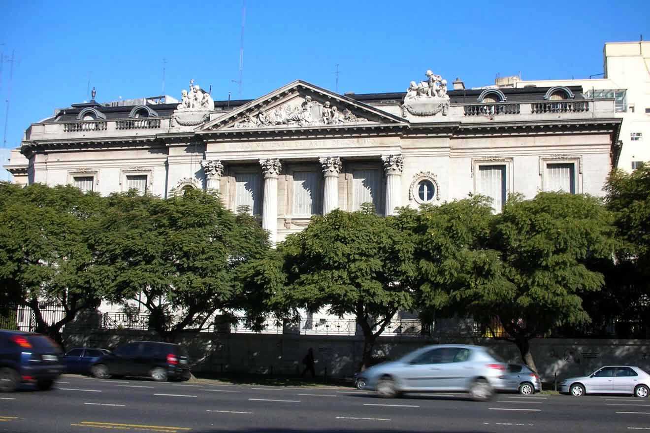 A large white building with cars driving down the street.