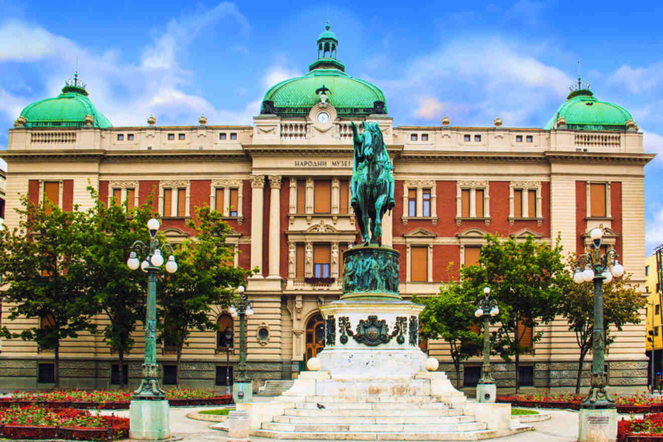 The National Museum of Serbia fronted by a statue, showcasing the country's rich cultural heritage under a blue sky with wispy clouds