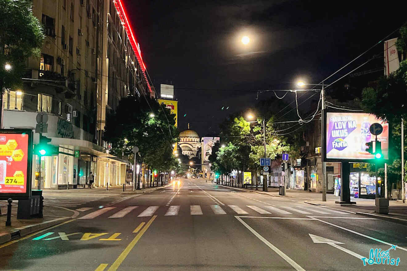 Belgrade at night showcasing the brightly lit streets leading to the Saint Sava Church under a full moon.