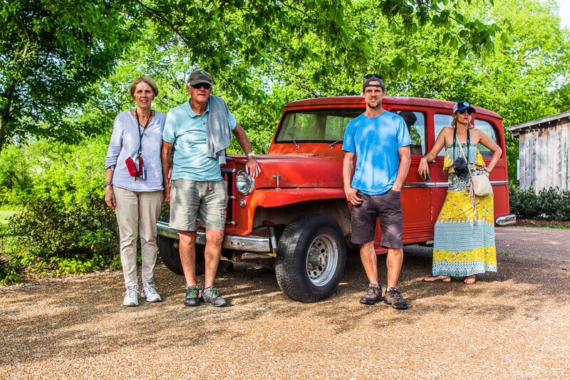 multi-gen family posing in front of red  vintage car