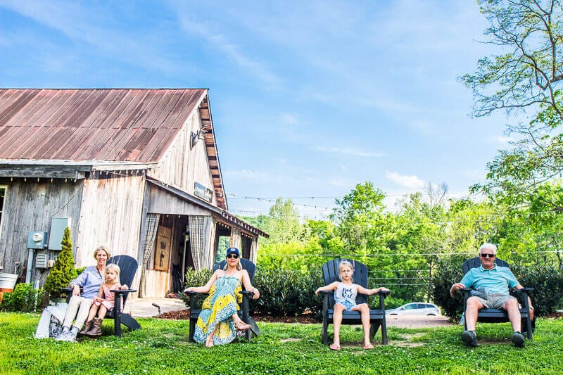 multi gen family sitting on chairs on lawn in front of shed