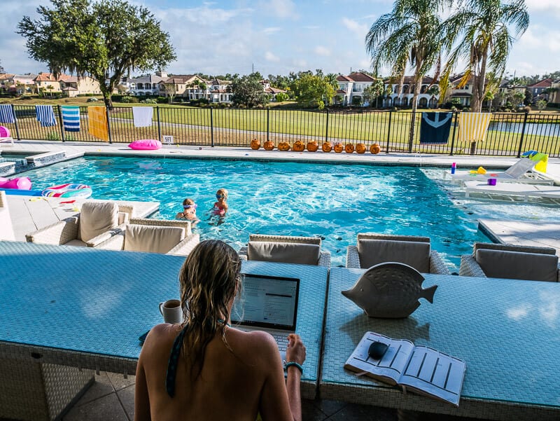 woman on computer beside swimming pool