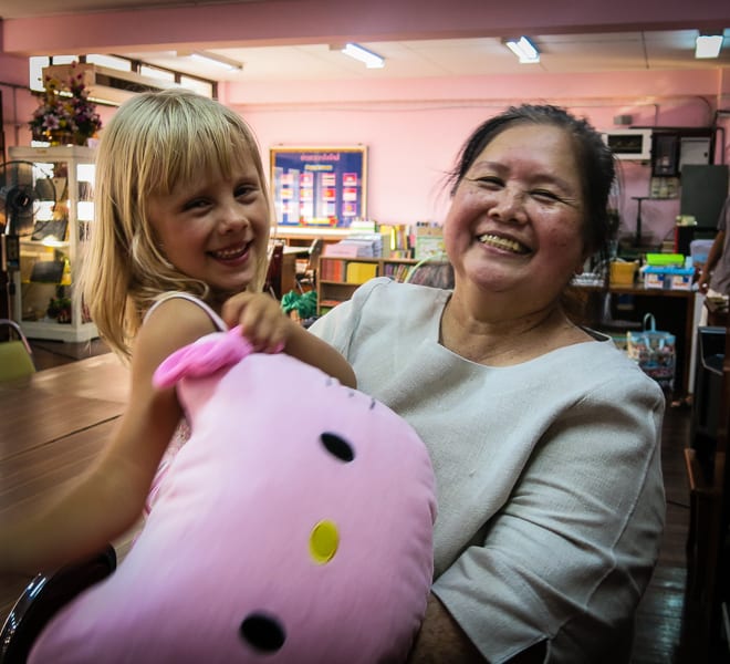 young girl laughing with thai lady and stuffed animal 