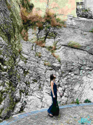 The writer of the post walks along a cobblestone path by a rugged limestone rock face in Avignon, France