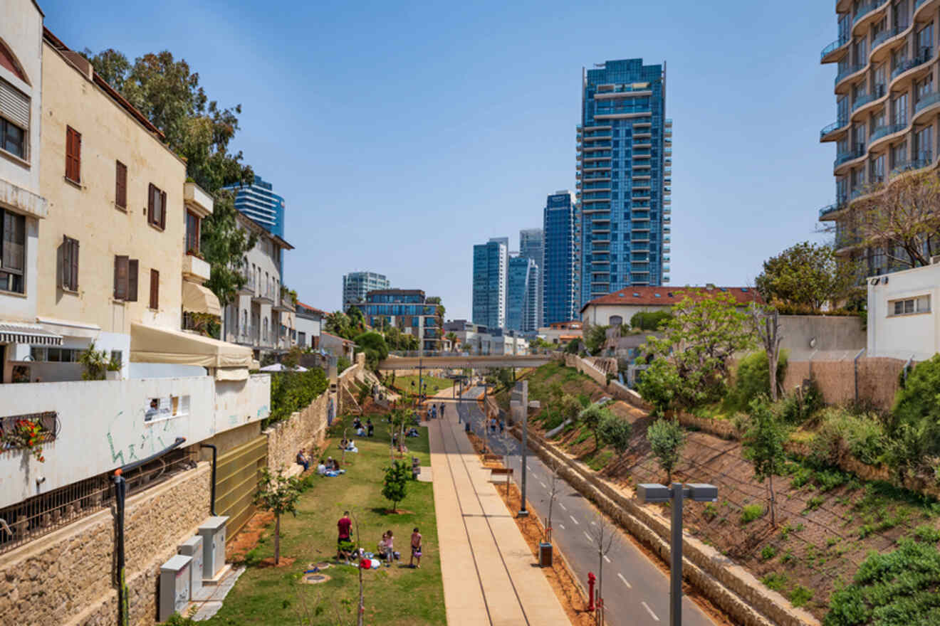 An urban park with a walkway between traditional and modern buildings, showcasing a contrast between historical architecture and contemporary skyscrapers