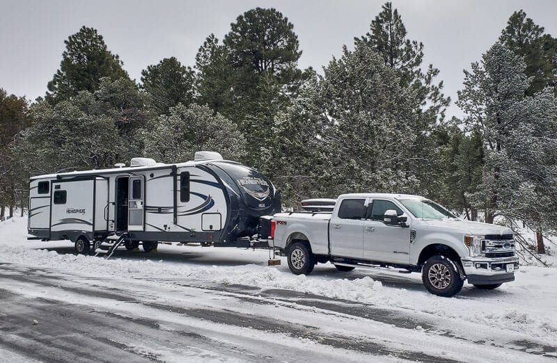 caravan and truck driving through the snow