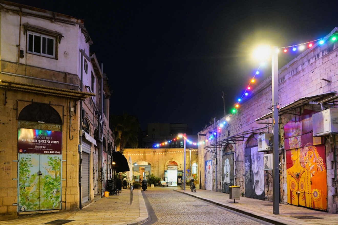 A nighttime view of a Tel Aviv street adorned with colorful lights, showcasing cultural artwork and a quiet, inviting atmosphere