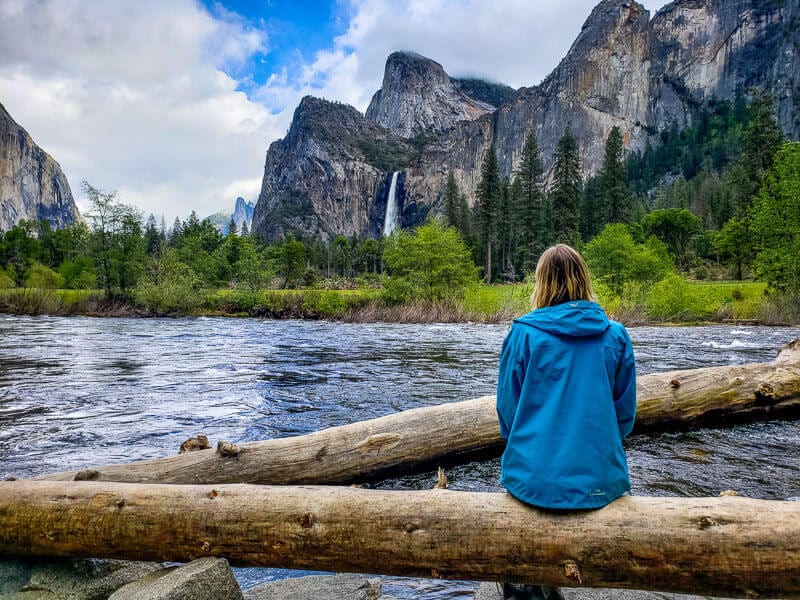 woman sitting on log looking at views of yosemite from valley view