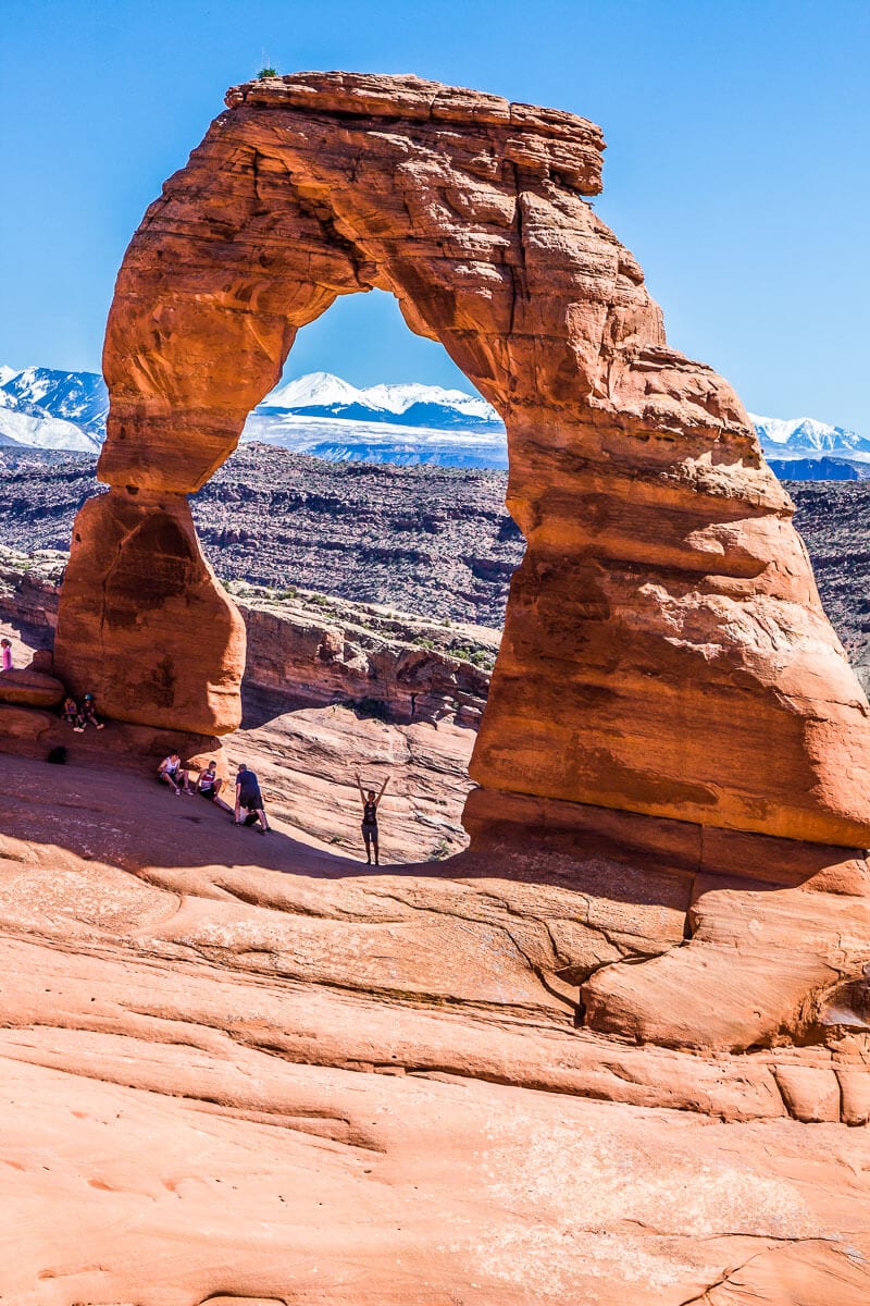 woman standing under delicate arch in utah