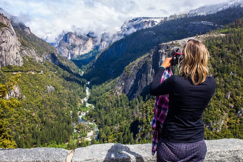 woman taking photo of yosemite valley and waterfalls