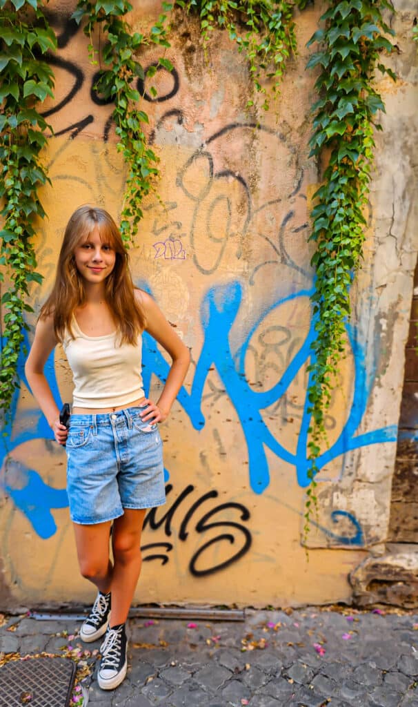 kalyra posing against graffiti wall with vines draped over it in Trastevere
